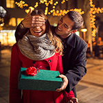 Man  keeps his girlfriend eyes covered while  she giving a gift